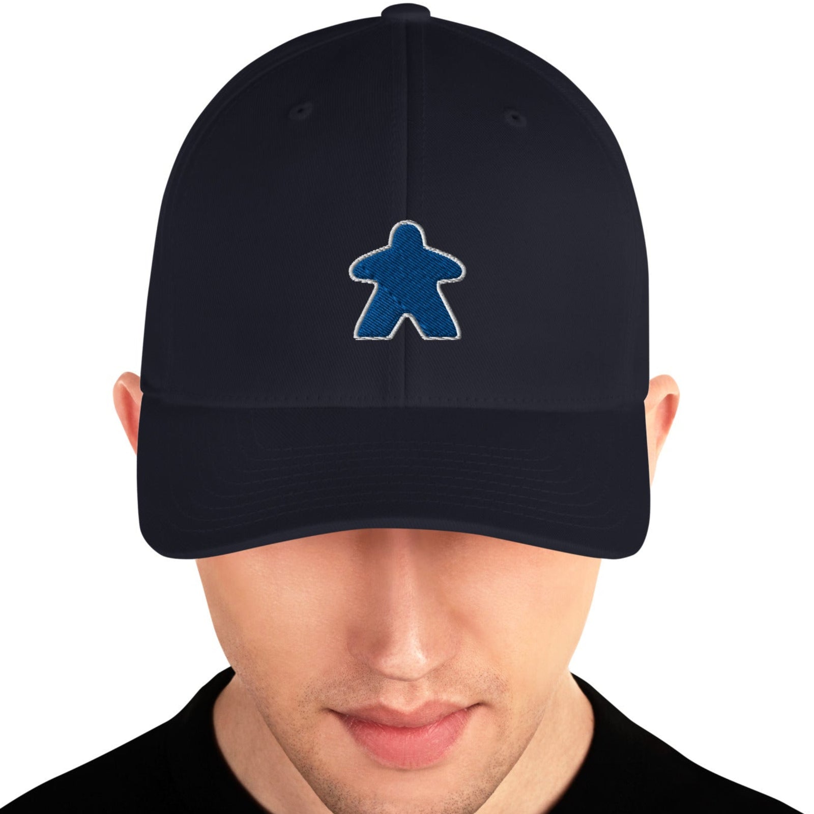 A person wearing a black hat with a blue embroidered meeple character on the front.