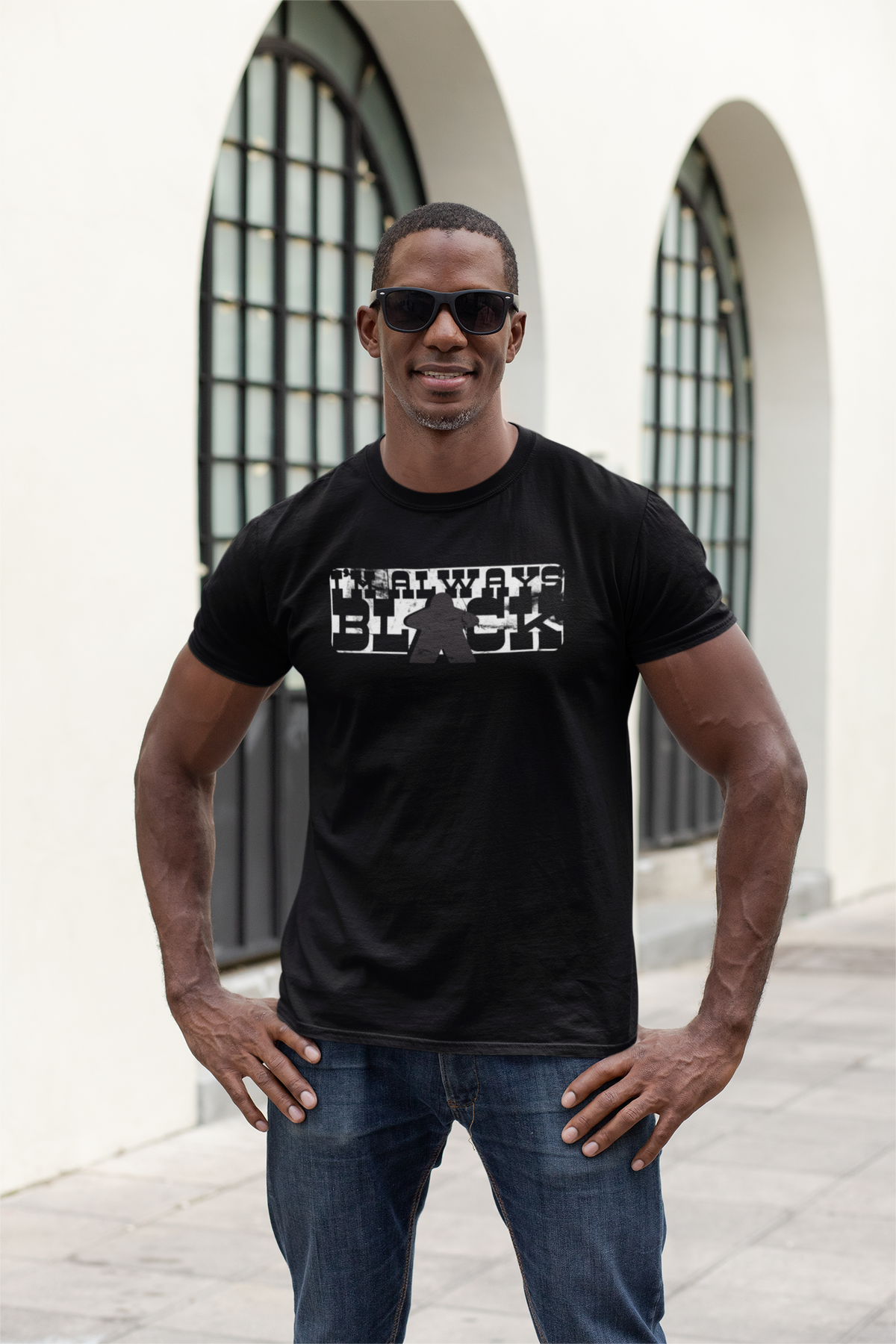 Man wearing a black t-shirt with our I'm Always Black design standing in front of architectural arches.