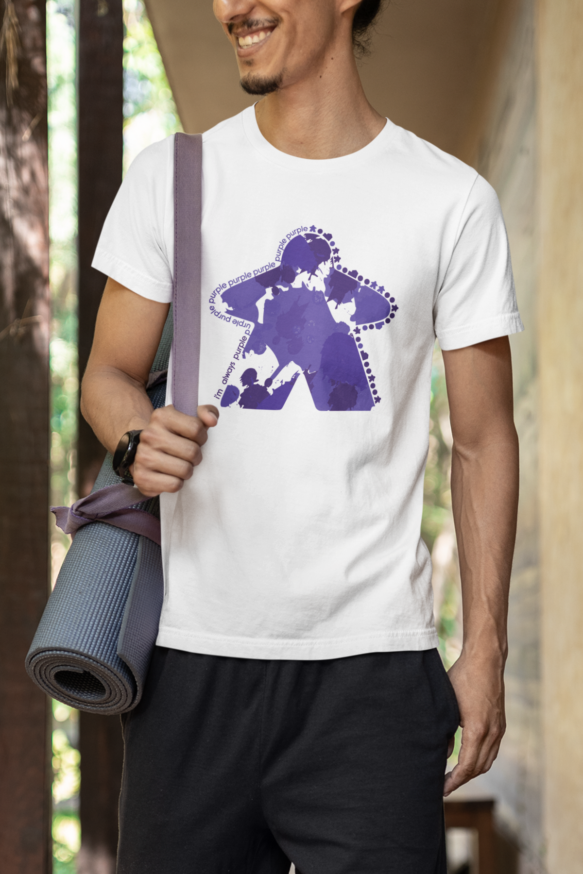 Skinny man wearing a white t-shirt with our I'm Always Purple design, holding a yoga mat.
