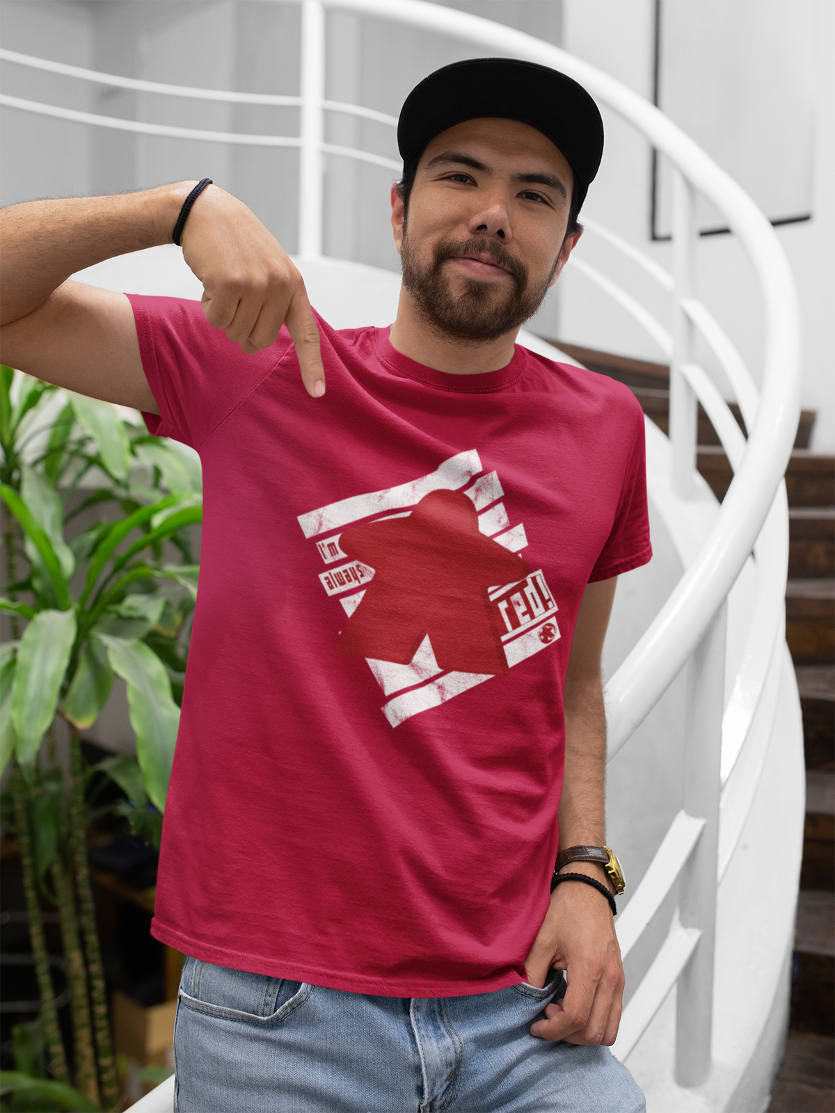 Man wearing a red t-shirt with our I'm Always Red design, pointing at it, in an indoor setting.