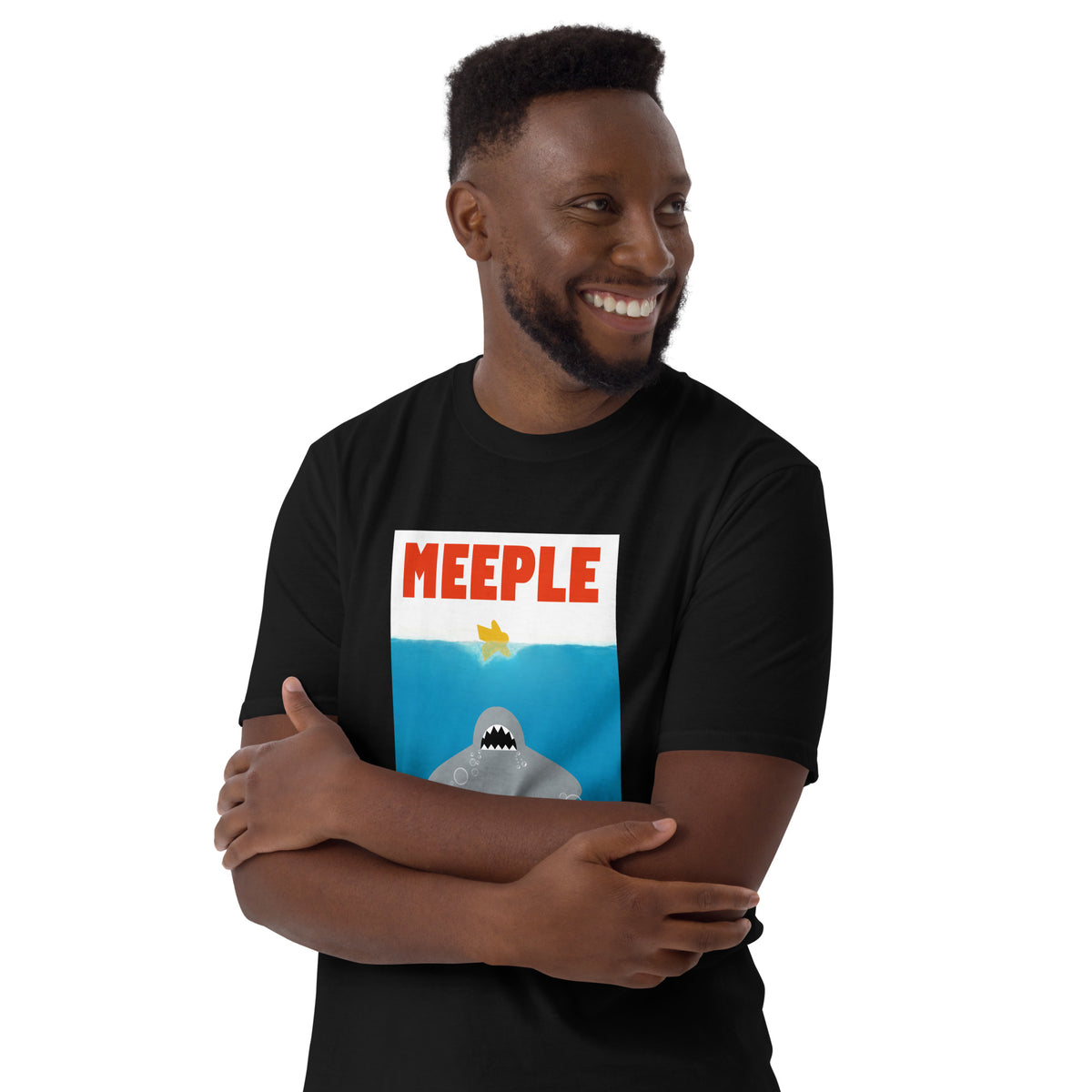 Man standing with arms crossed wearing our Meeple Shark Attack t-shirt