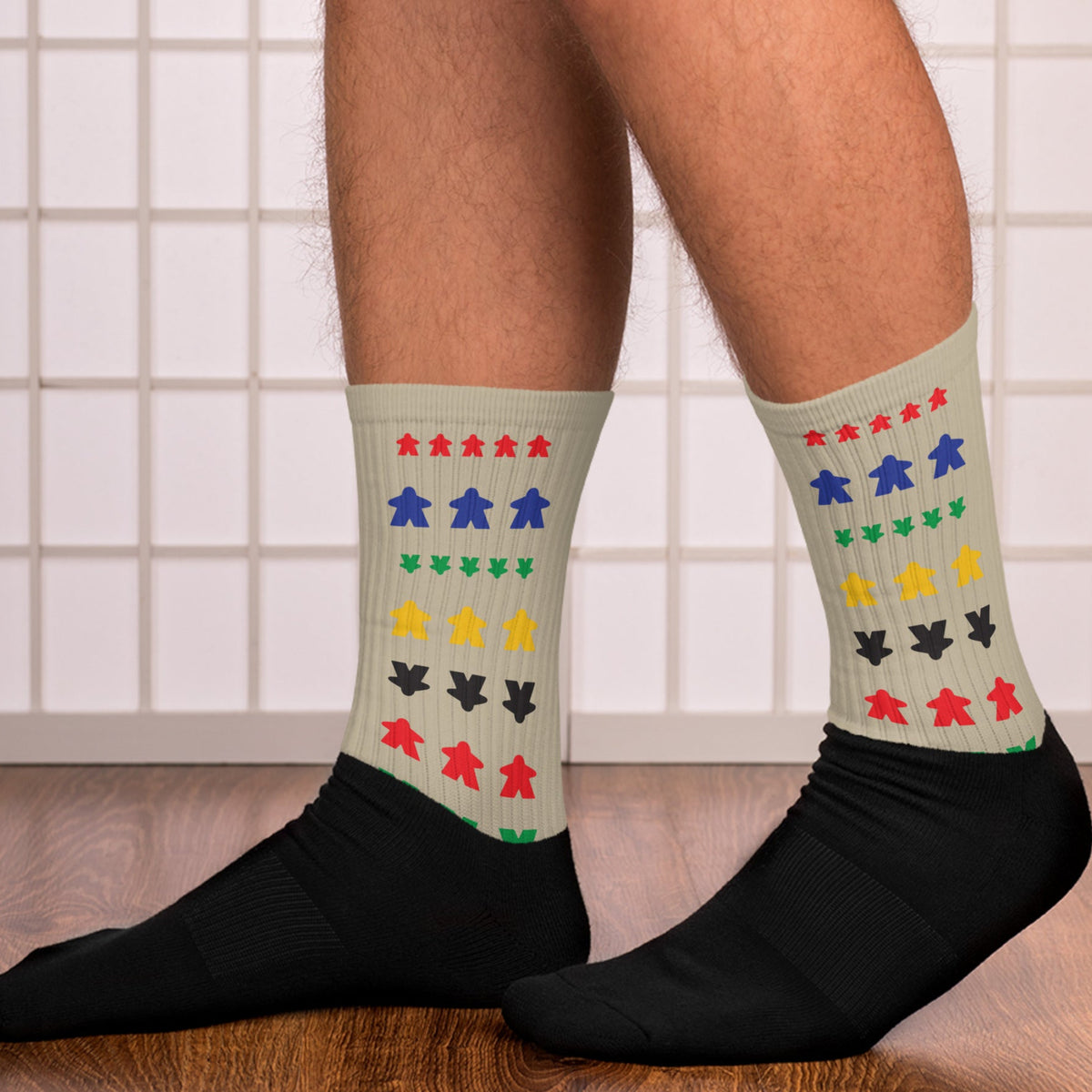 Man wearing our meeple socks walking on wood floor