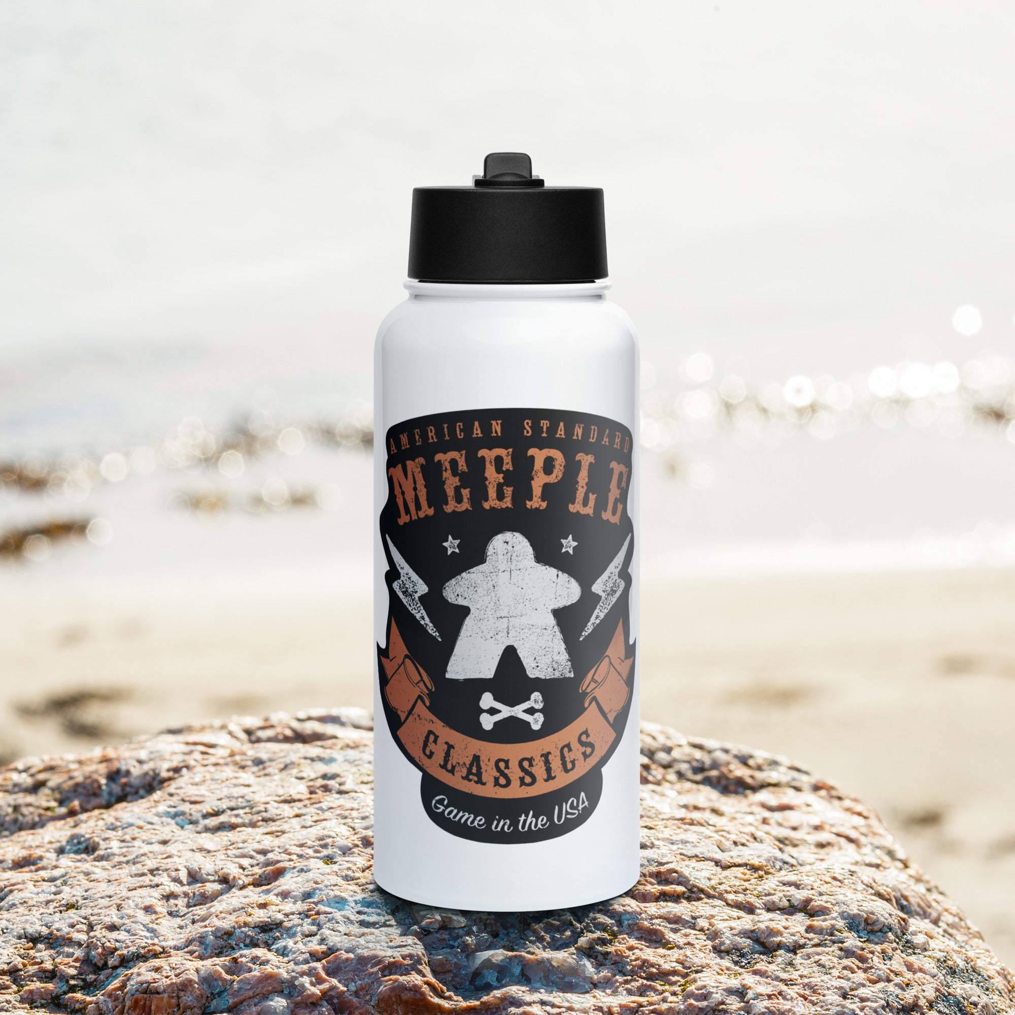 American Meeple Classics design on water bottle positioned on a rock at the beach